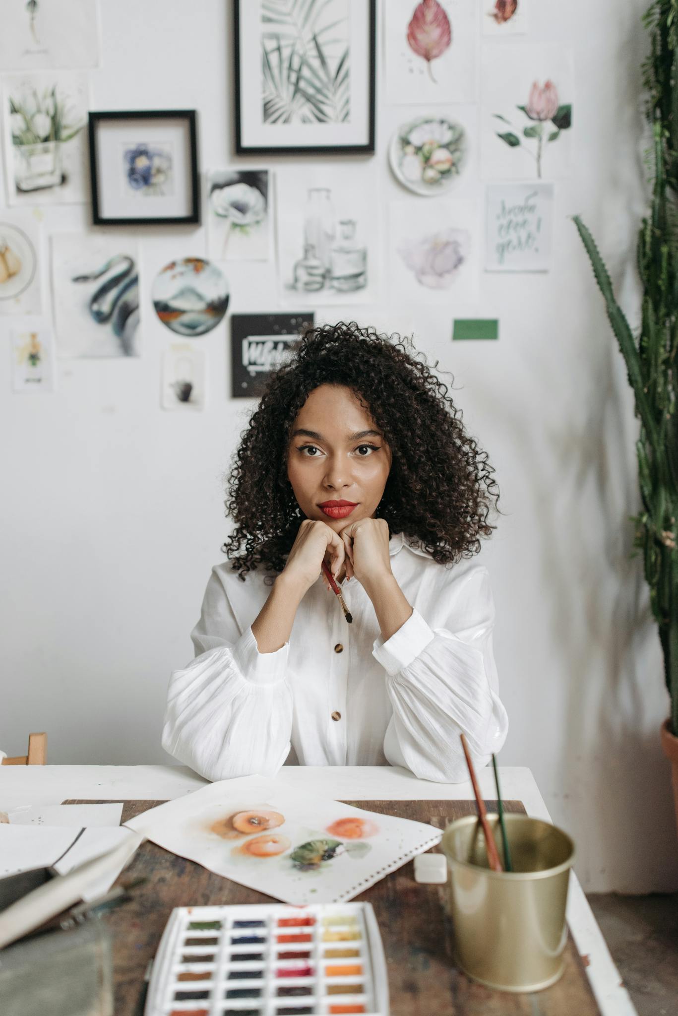 A woman artist in a creative indoor painting workshop surrounded by her art pieces.